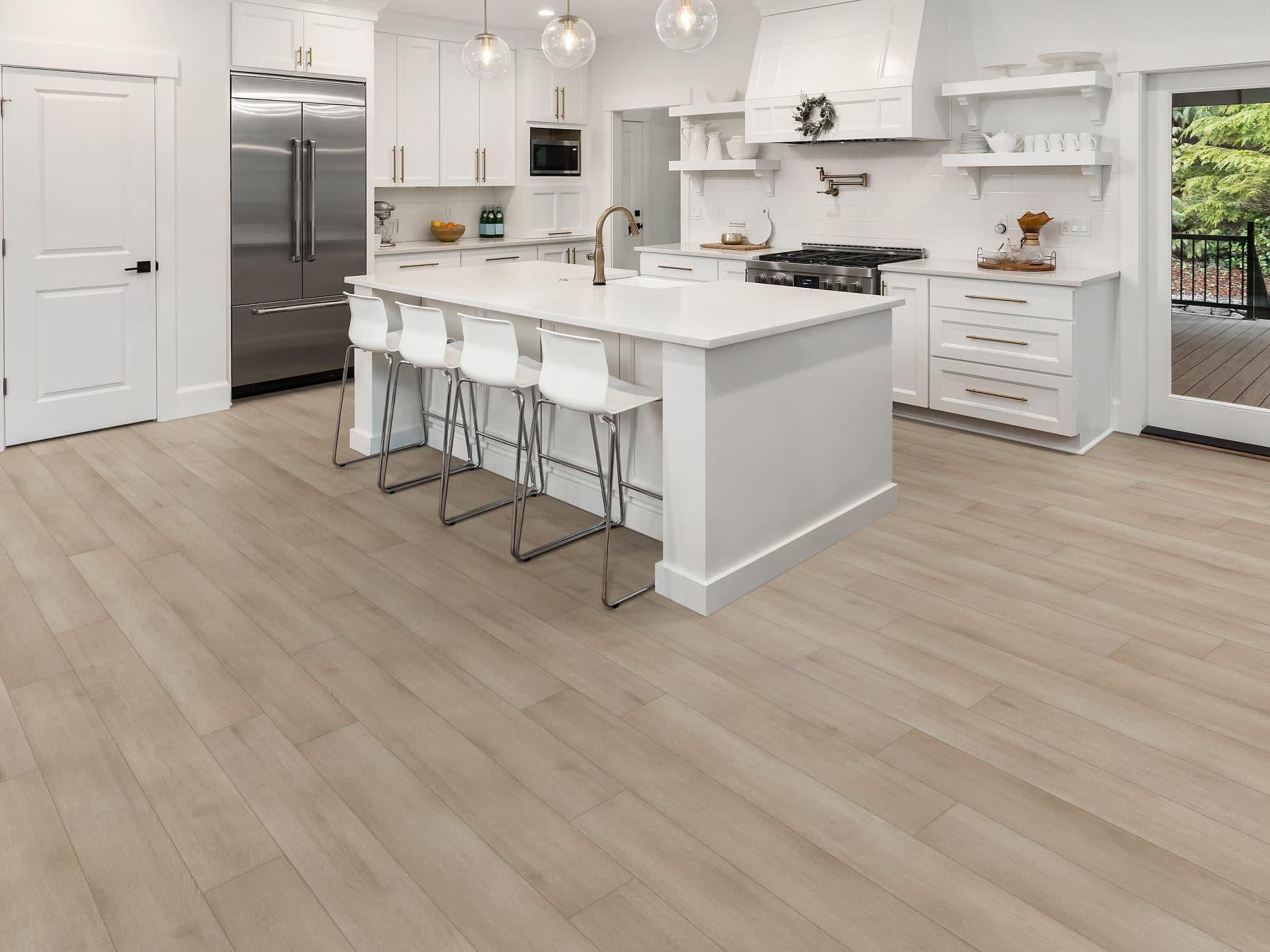 Spacious modern kitchen with light wood floors, a white island with four white stools, stainless steel appliances, and globe pendant lights.
