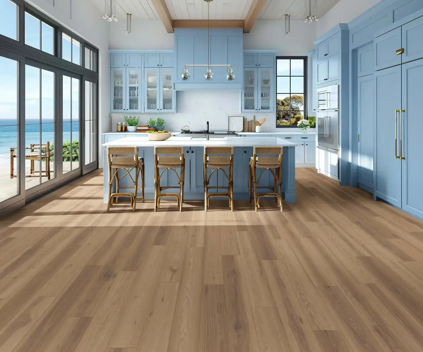 Spacious kitchen with light blue cabinets, large island, and wicker chairs. Sunlight streams through glass doors, revealing an ocean view.