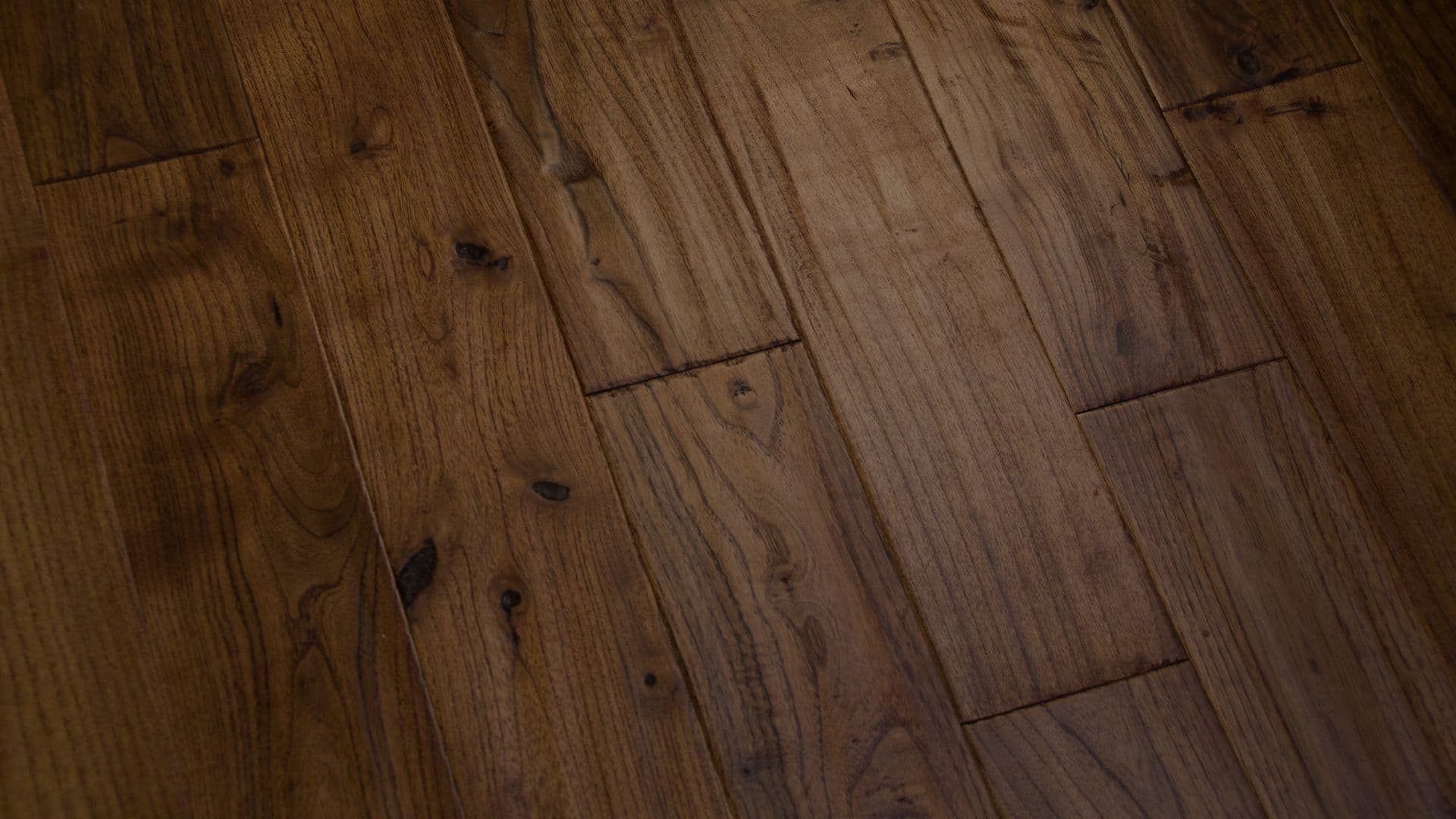 Dark hardwood flooring with visible grain patterns and natural knots. The wood's rich brown tones and textures convey a warm, rustic feel.