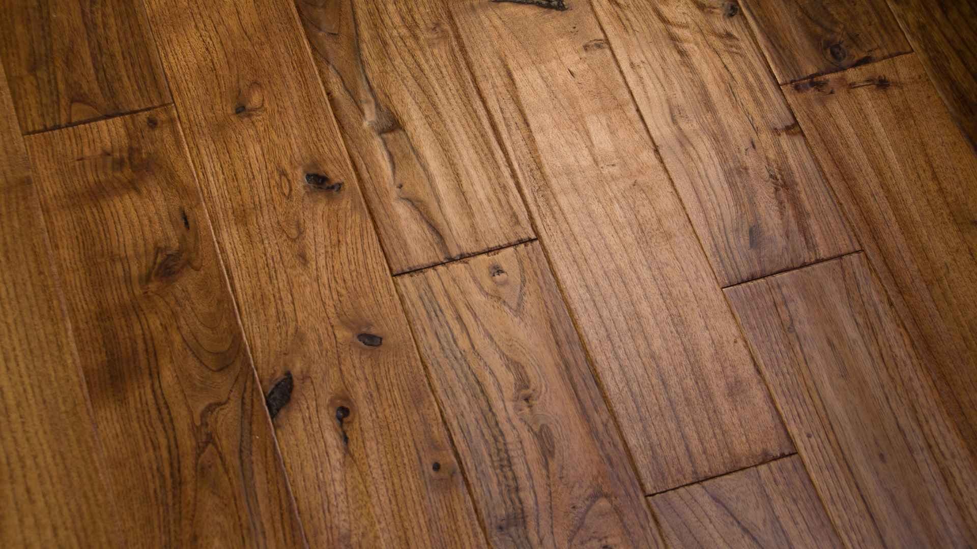 Close-up of a polished wooden floor with natural grain and knots. The rich brown tones and smooth texture convey warmth and elegance.