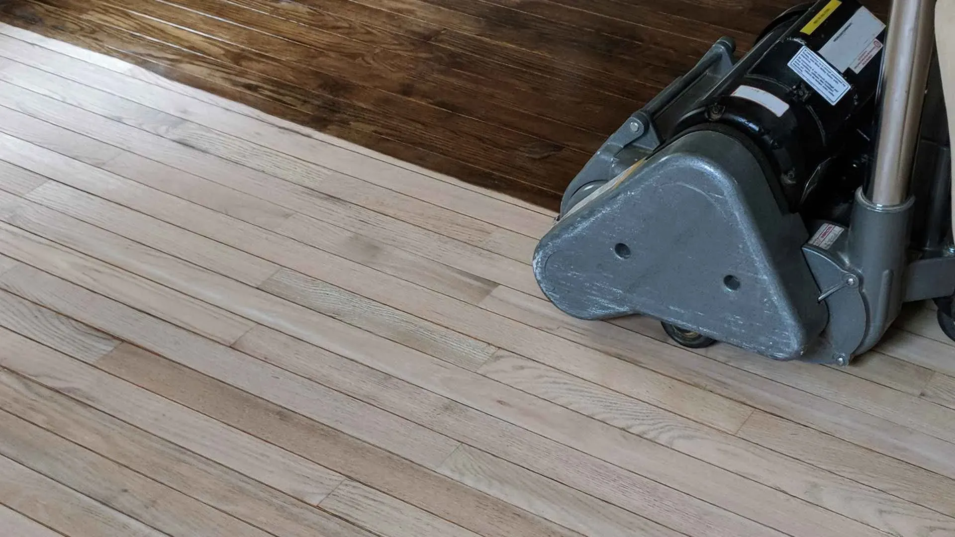 A floor sander refines light wood planks; the finished section reveals rich, dark wood. The image conveys a sense of transformation and renewal.