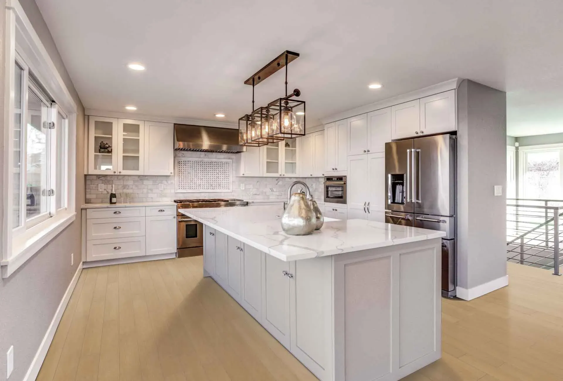 Spacious modern kitchen with a marble island countertop, stainless steel appliances, pendant lighting, and white cabinetry. Warm, inviting atmosphere.