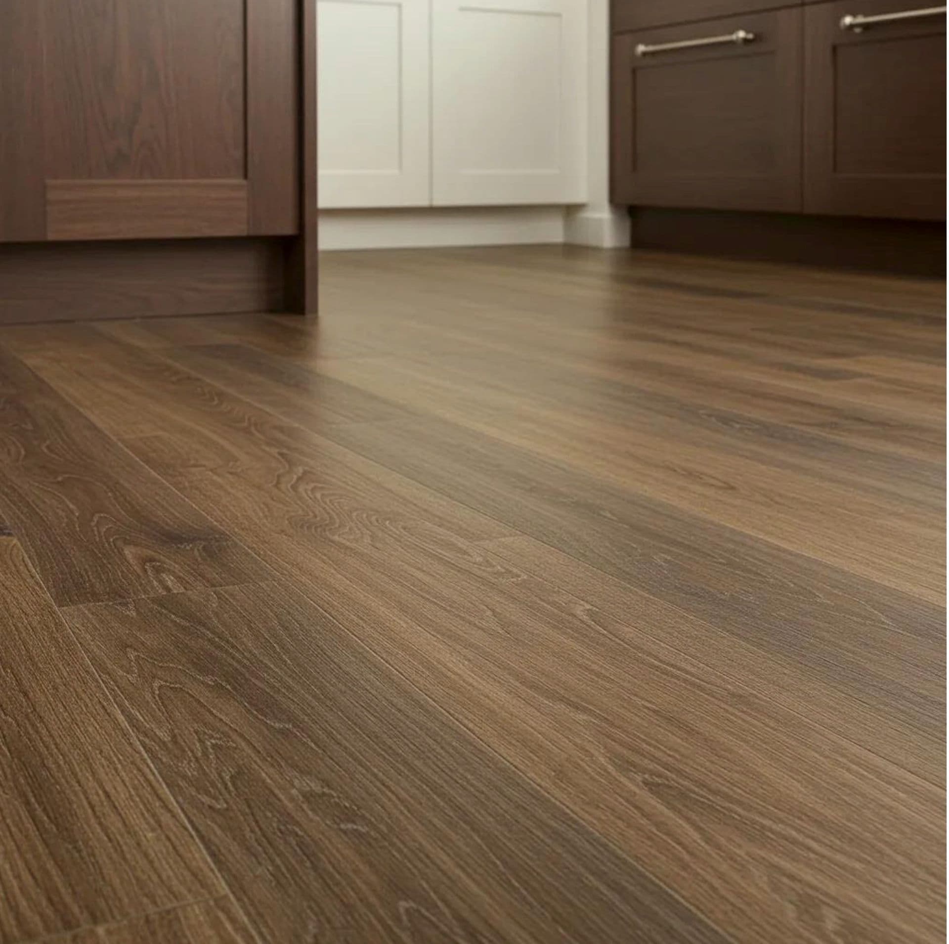 Smooth brown wooden laminate floor in a modern kitchen with dark brown and white cabinetry. The scene conveys a clean, warm, and inviting atmosphere.