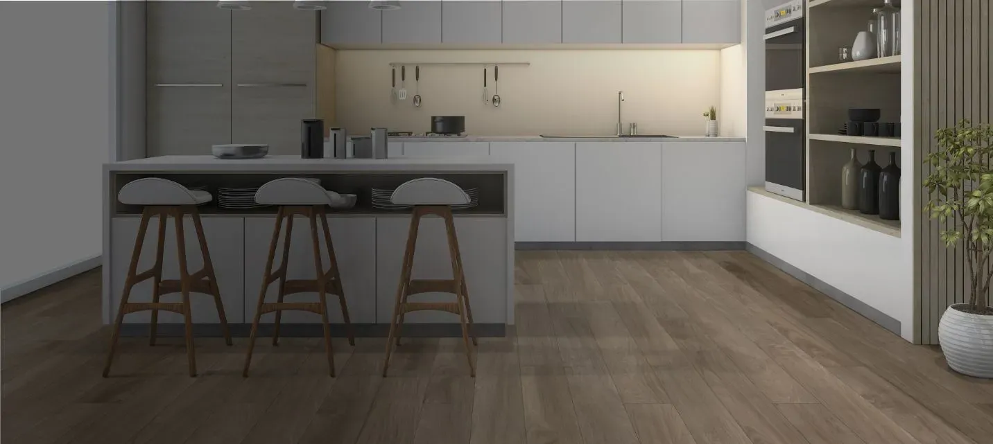 Modern kitchen with sleek white cabinets, center island with three stools, wooden floor, and soft lighting. A potted plant adds a touch of nature.